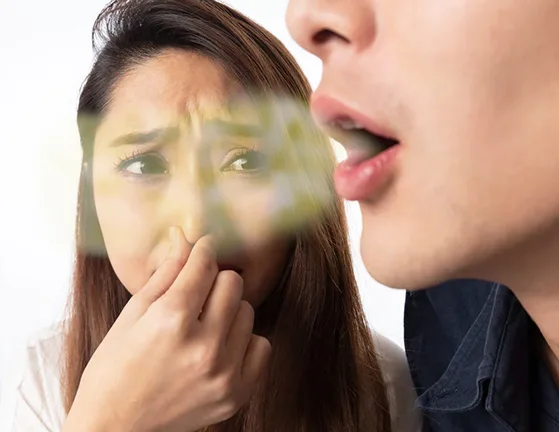 Person holding nose with an uncomfortable expression, symbolizing bad breath odor.